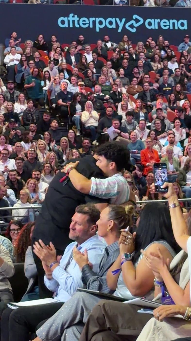 Tony Robbins hugging Lumore in an arena crowd